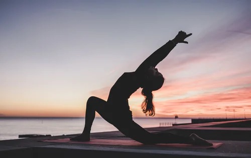 Woman stretching at sunrise by the shore