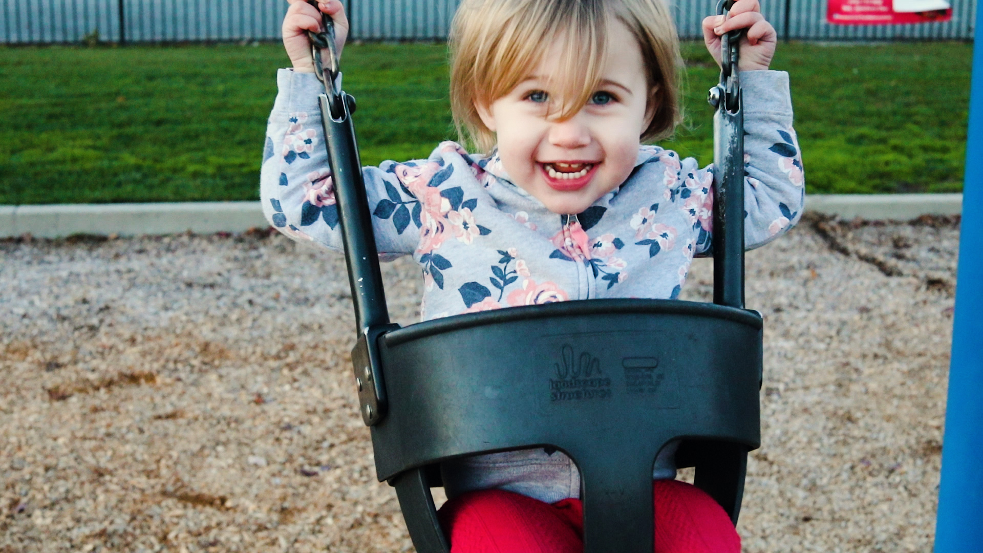 Young Girl smiling while swinging on a swing in the park