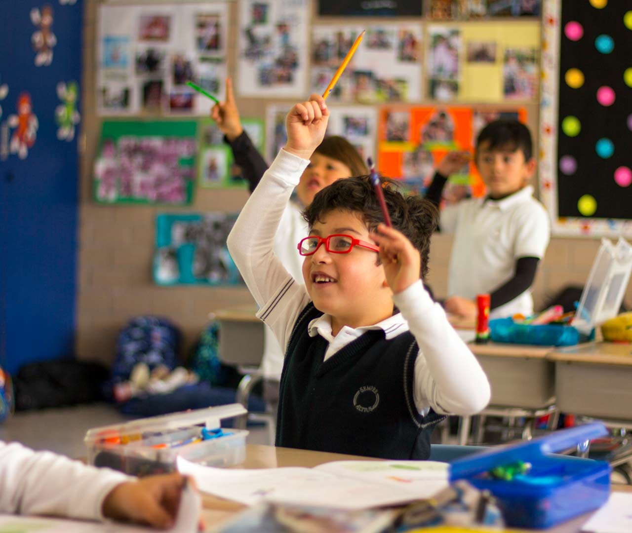Alumno de primaria levanta la mano para participar en clase.