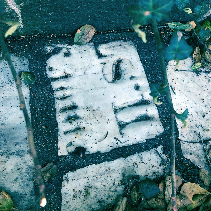 A piece of grave marker embedded in a wall in Buena Vista Park - there are some letters of the gravestone engraving still visible, but it's unreadable