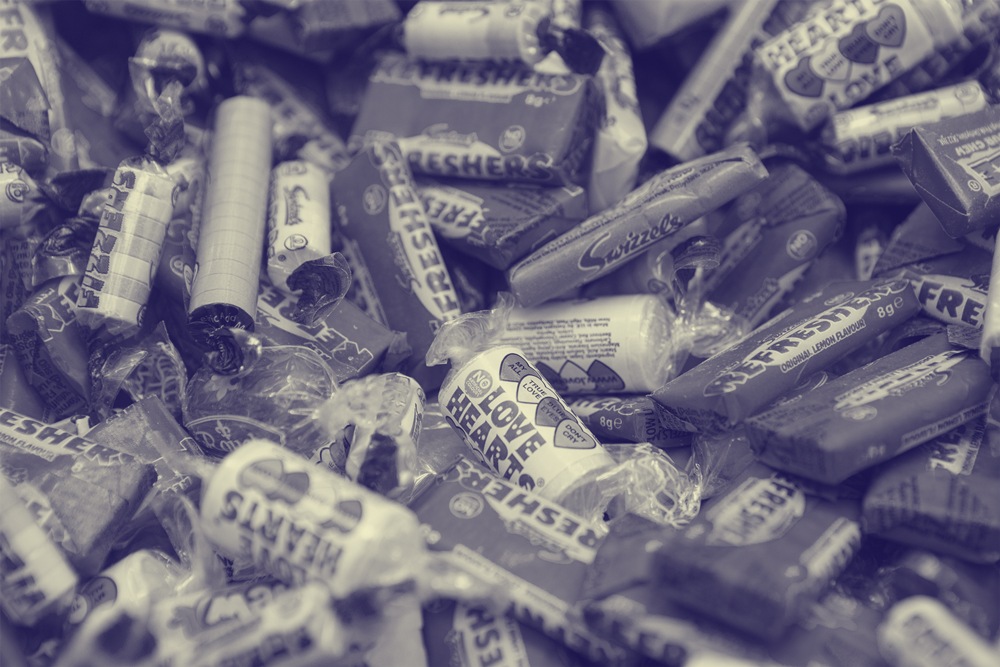 Image of various wrapped halloween candy in a purple/yellow tint