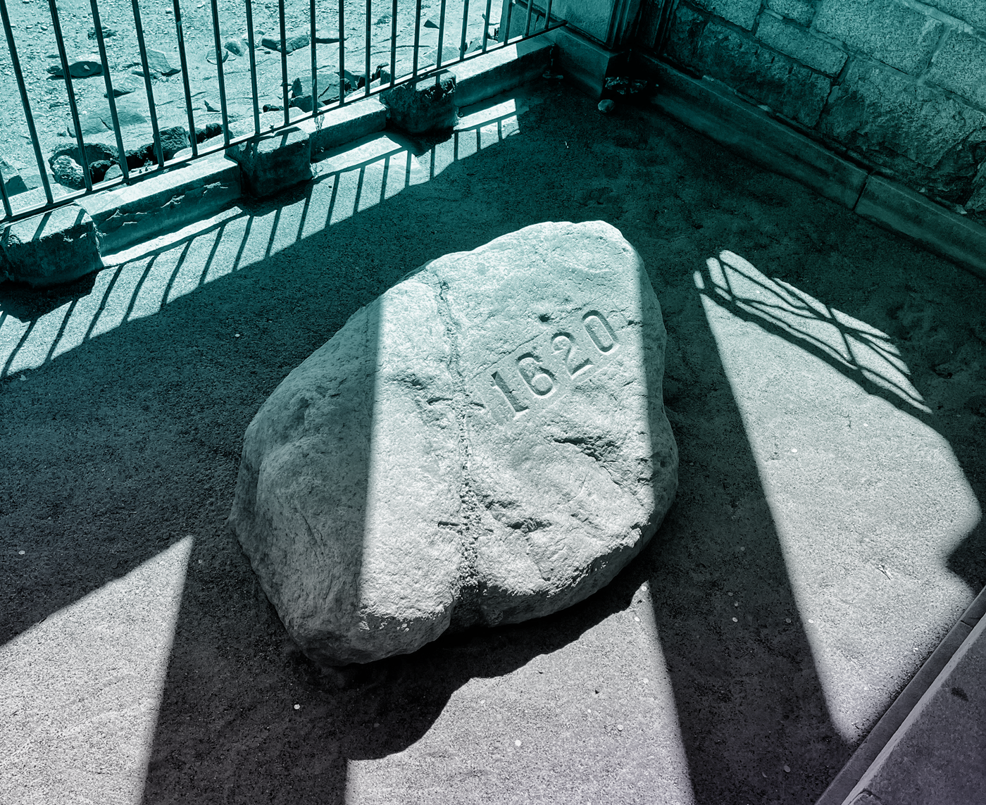 A pale rock inside the fenced enclosure of the Plymouth Rock Monument. The numerals “1620” have been etched onto its surface.