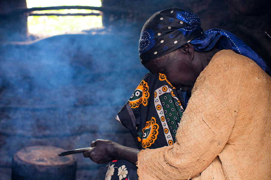 Women cooking while covering eyes with a scarf in a smokey room.