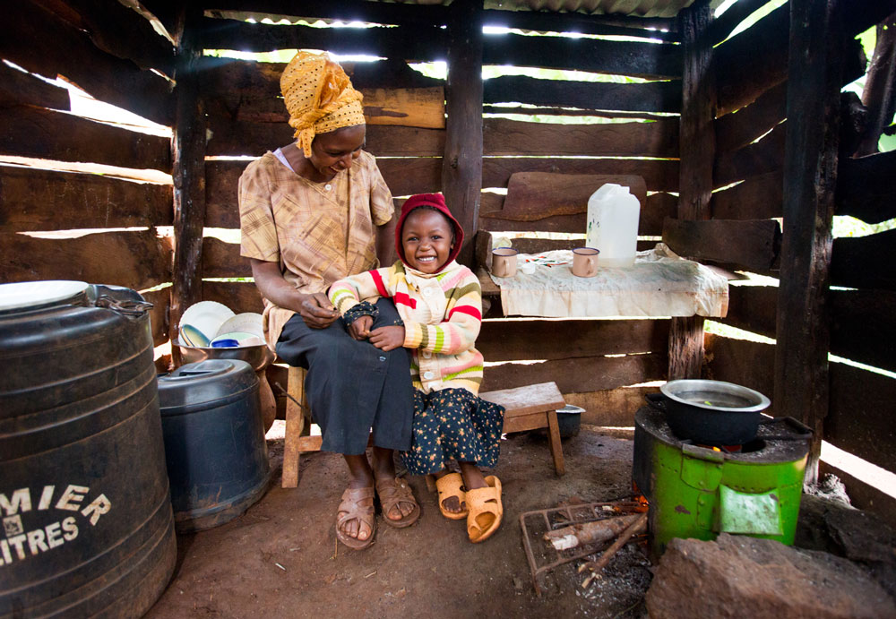 Woman sitting on a chair while smiling down and toddler leaning on her lap. 