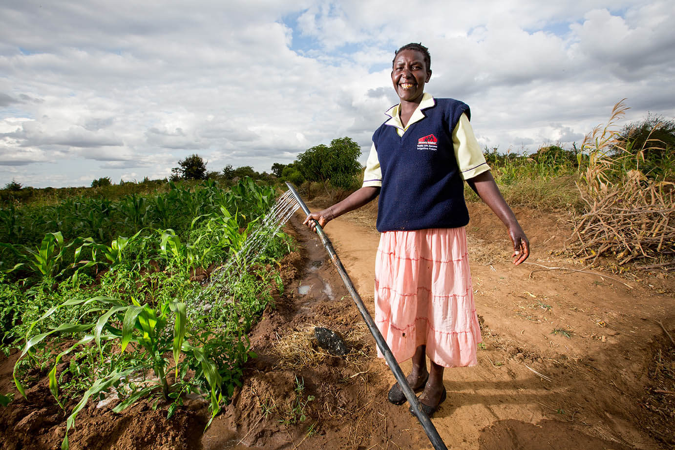 Women smiling while watering crops.