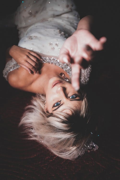 A woman in white bridal wear pointing toward the camera.