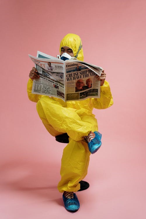A Man Wearing PPE, Reading A Newspaper