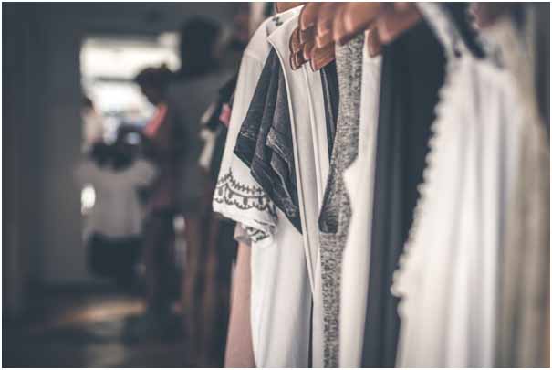 A clothing rail with various clothing items on wooden hangers