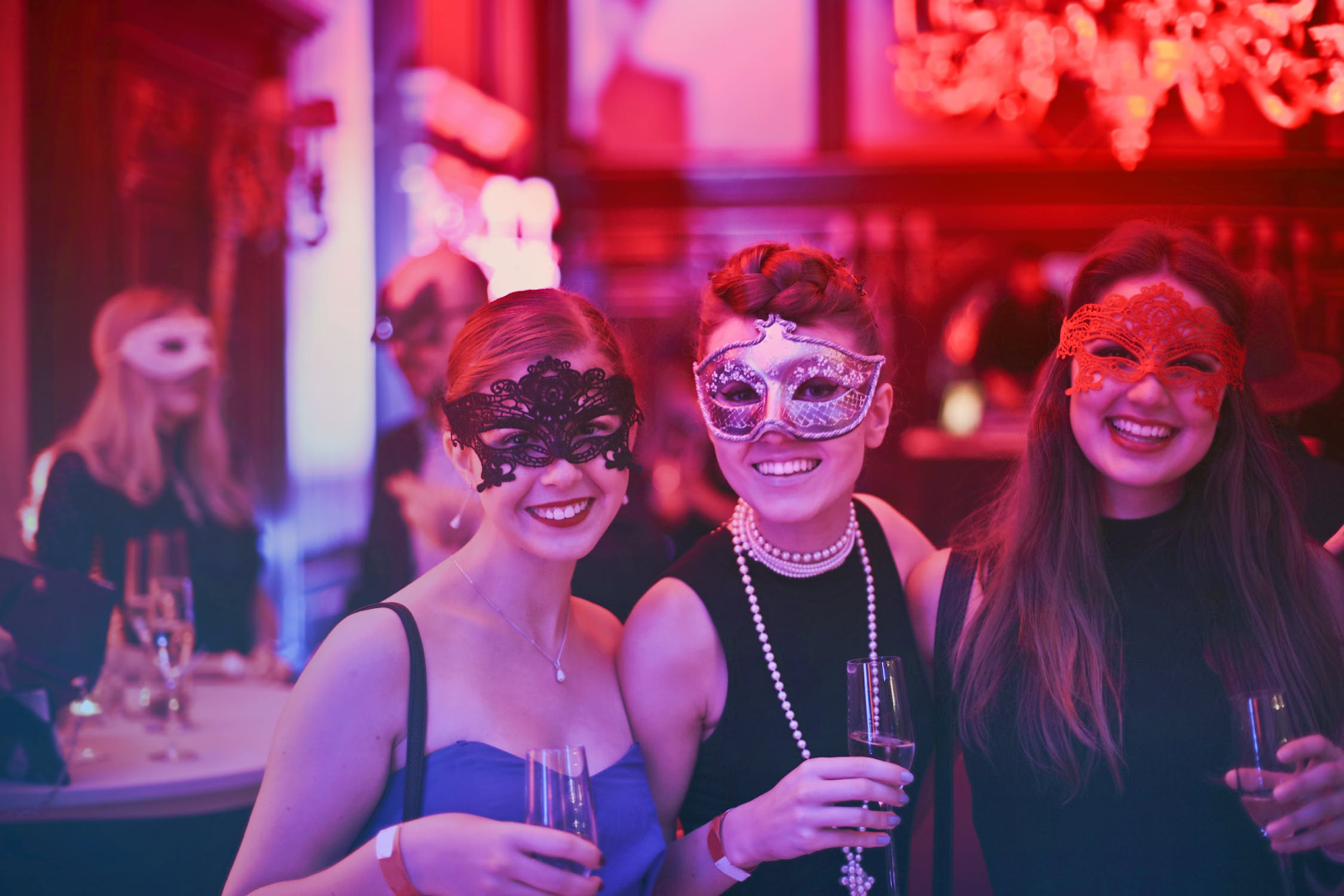 three young women wearing masks at a halloween masquerade pose together