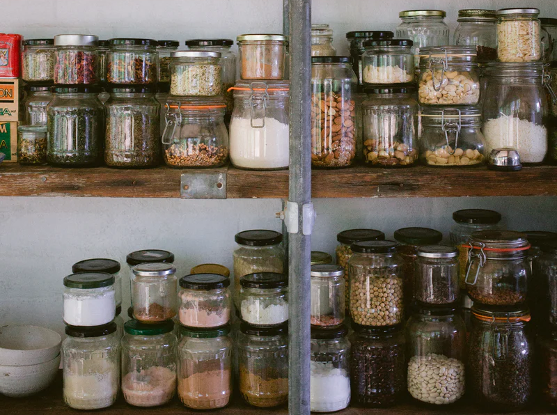 An image of two shelves in a pantry, full of jars of food.