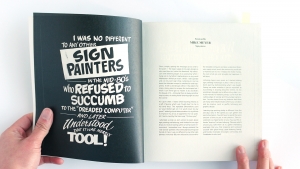 Hand-lettering artist sketching bold, serif initials with black ink.