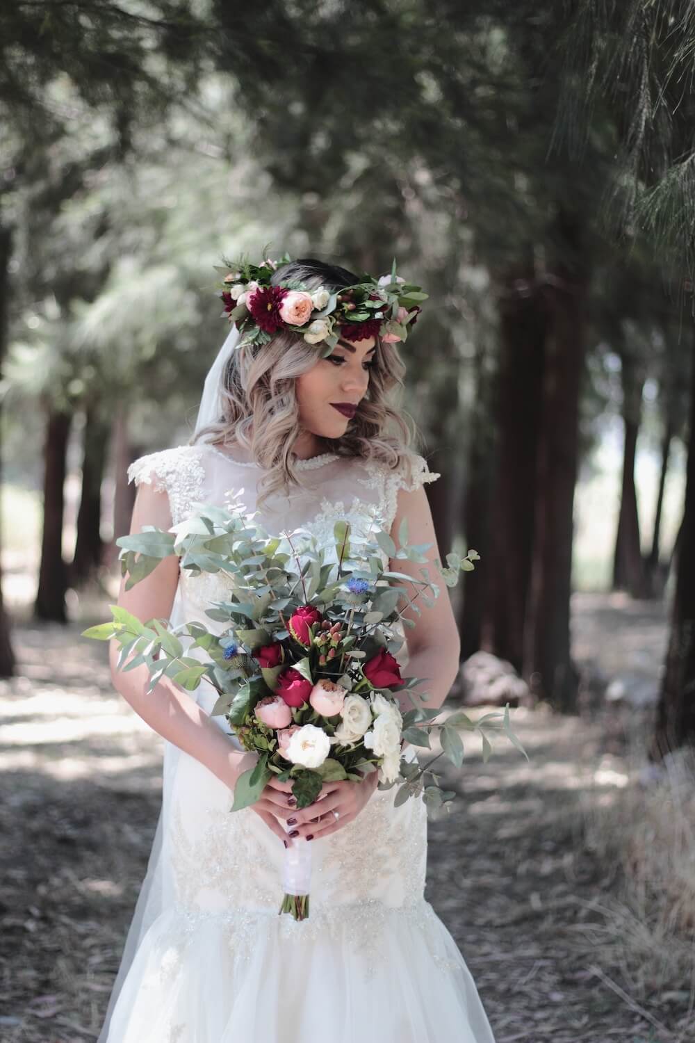 Woman wearing weddingdress and flower crown carrying large bouquet