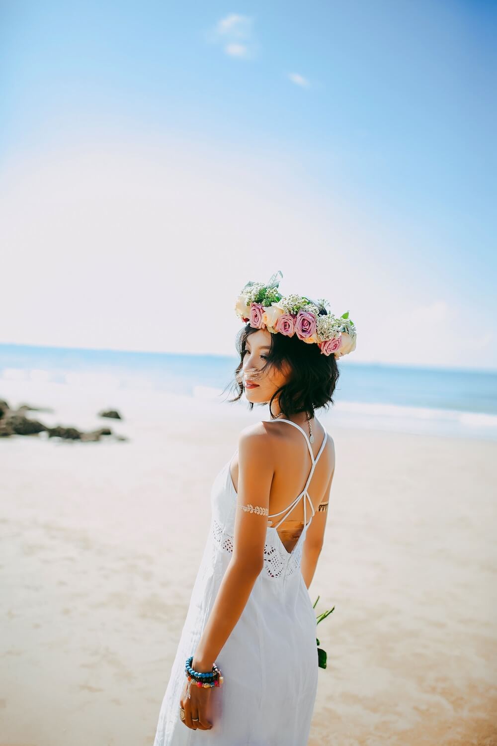 Woman standing on beach holding flowers
