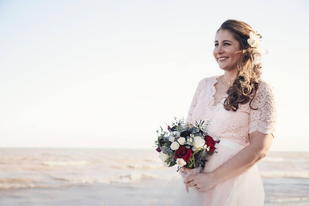 Woman smiling holding wedding bouquet on beach