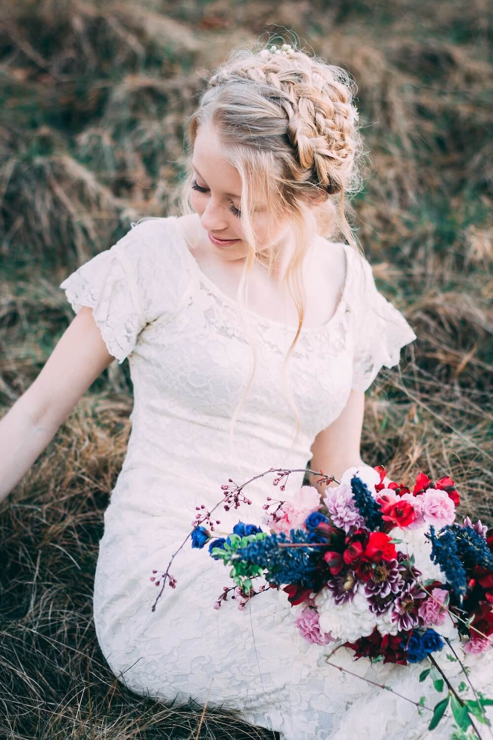 Woman sitting in grass wearing wedding dress