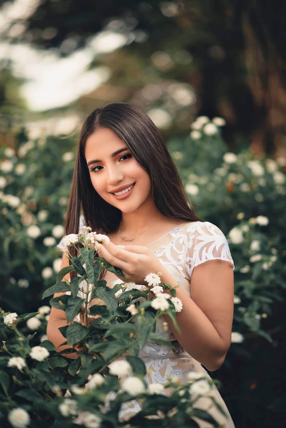 Woman wearing white dress touching flowers