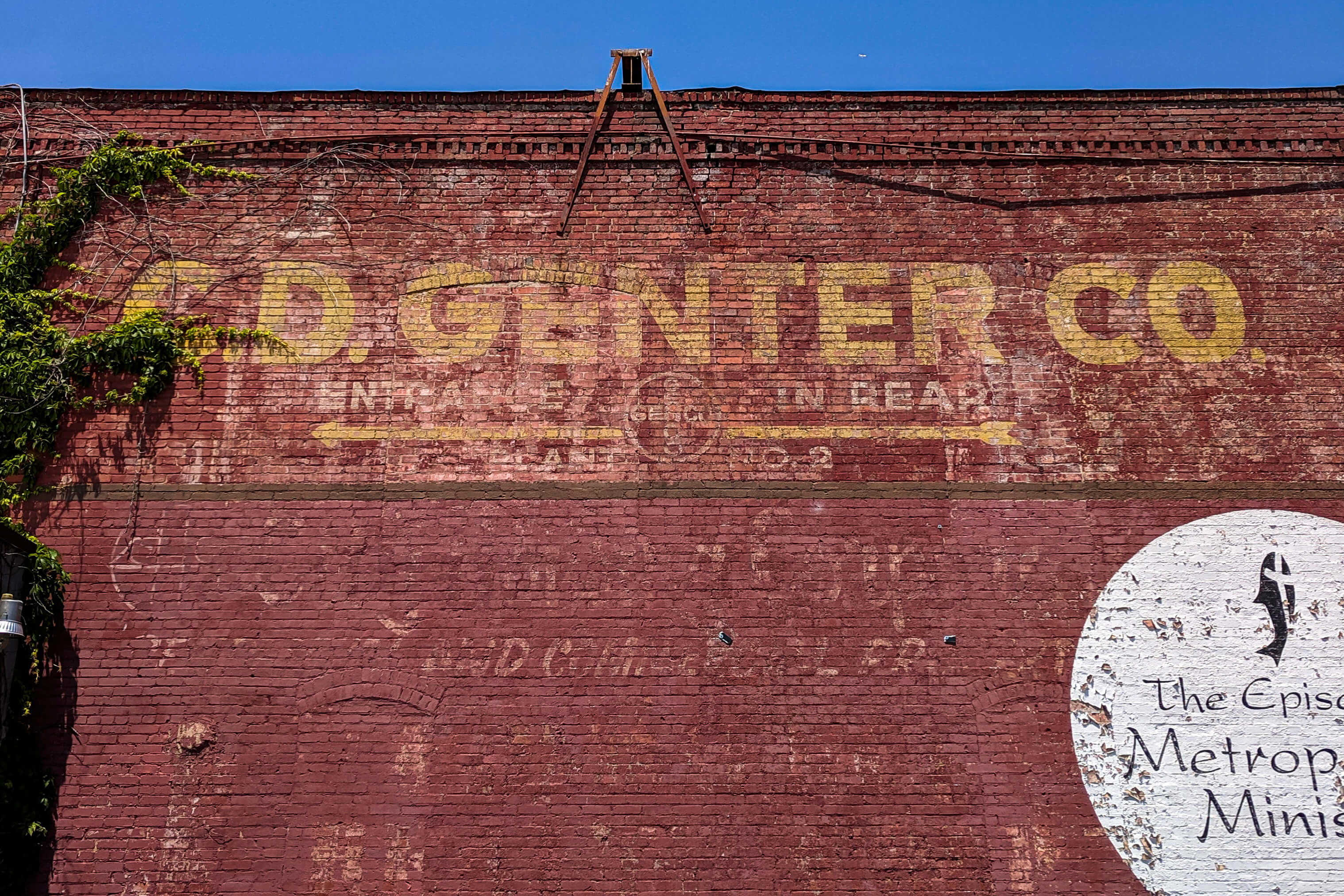 A very weathered C.D. Genter Co. logo painted onto a brick building