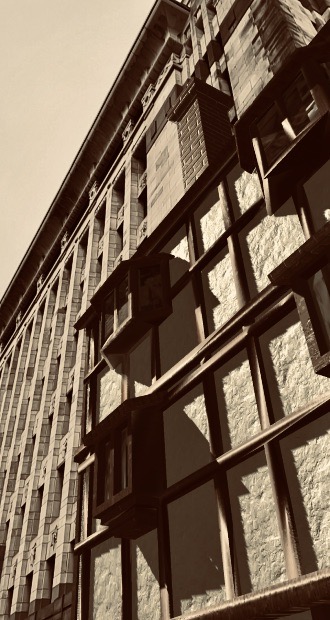 A model of a building is rendered in front of an actual building