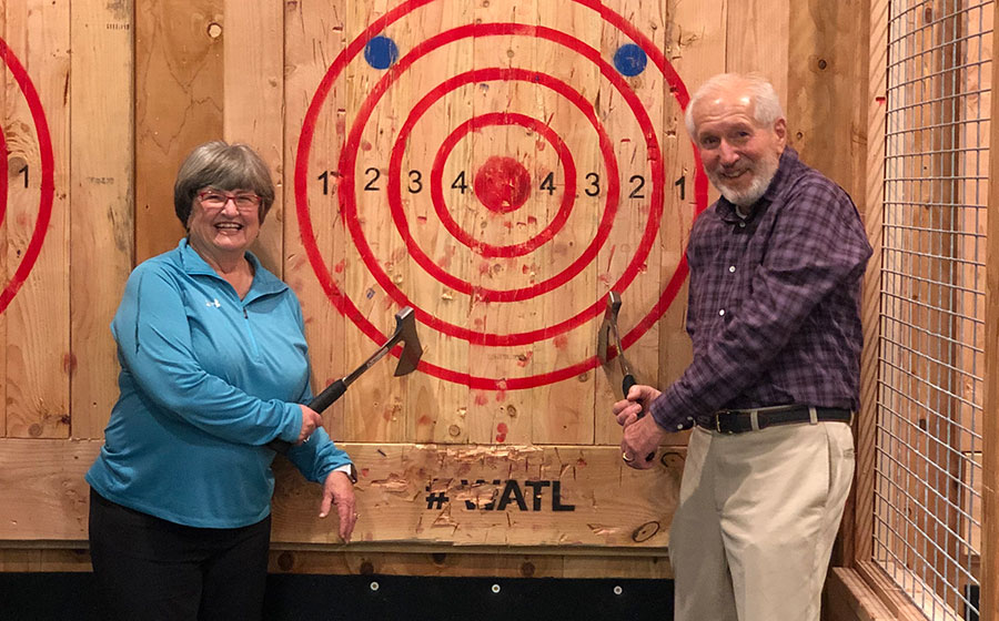 An older couple retrieve their axes from the target.