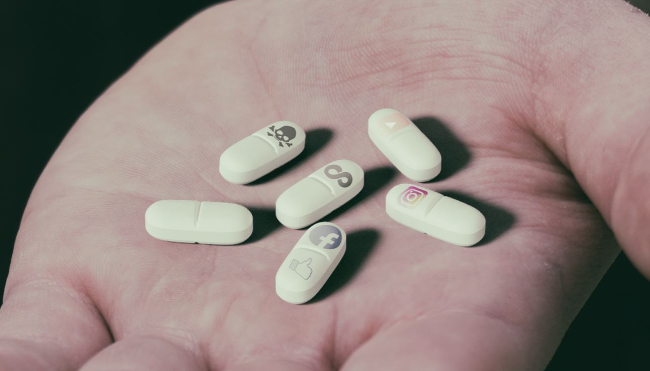 Hand holding pills with social media logo's on them.