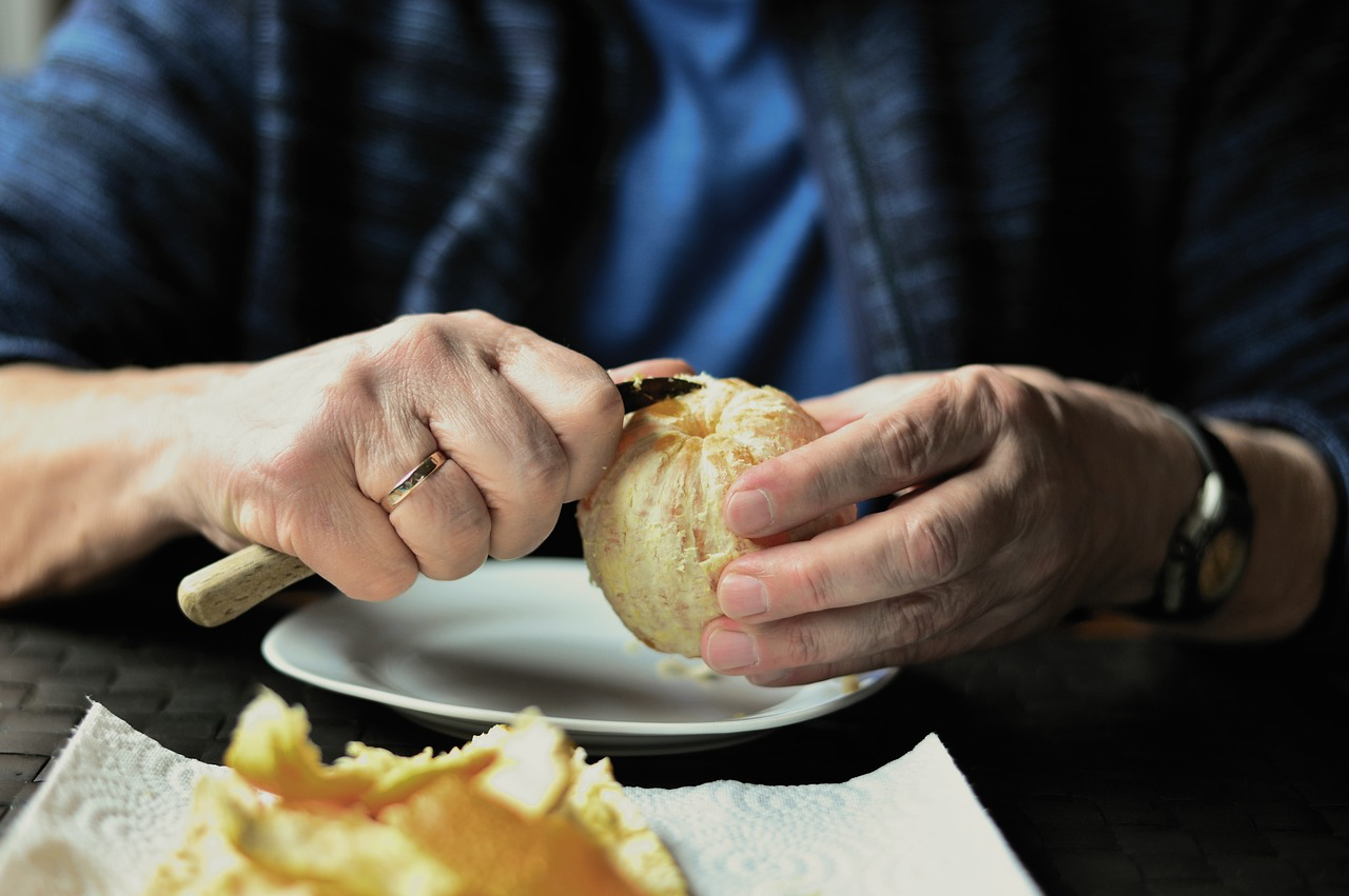 Person uses paring knife to peel orange