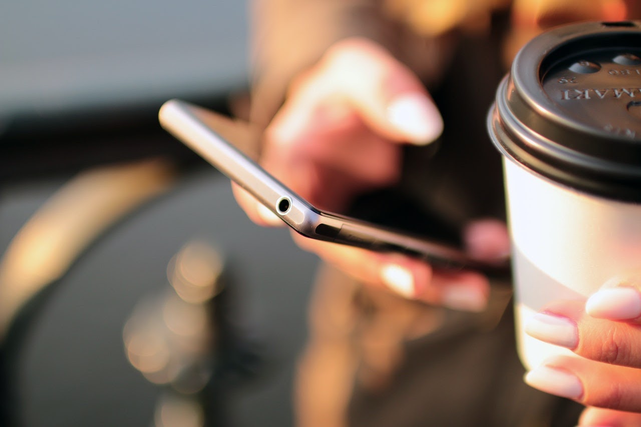 Hand holding smartphone and coffee cup