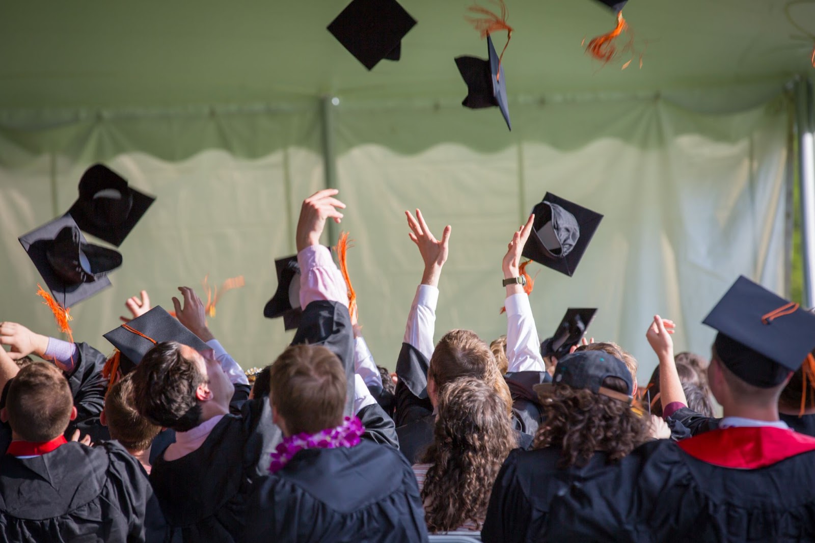 Graduating class throw their caps in the air.