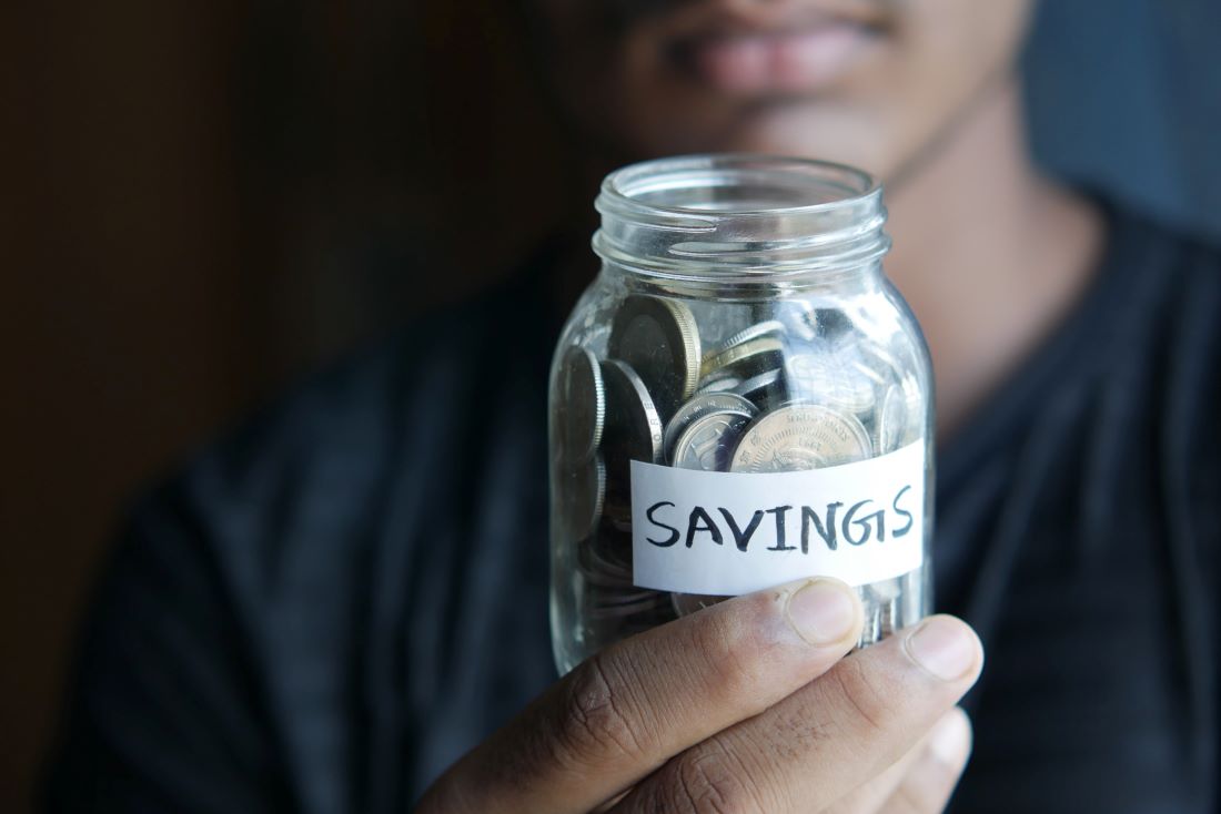 A young man holding a jar of savings