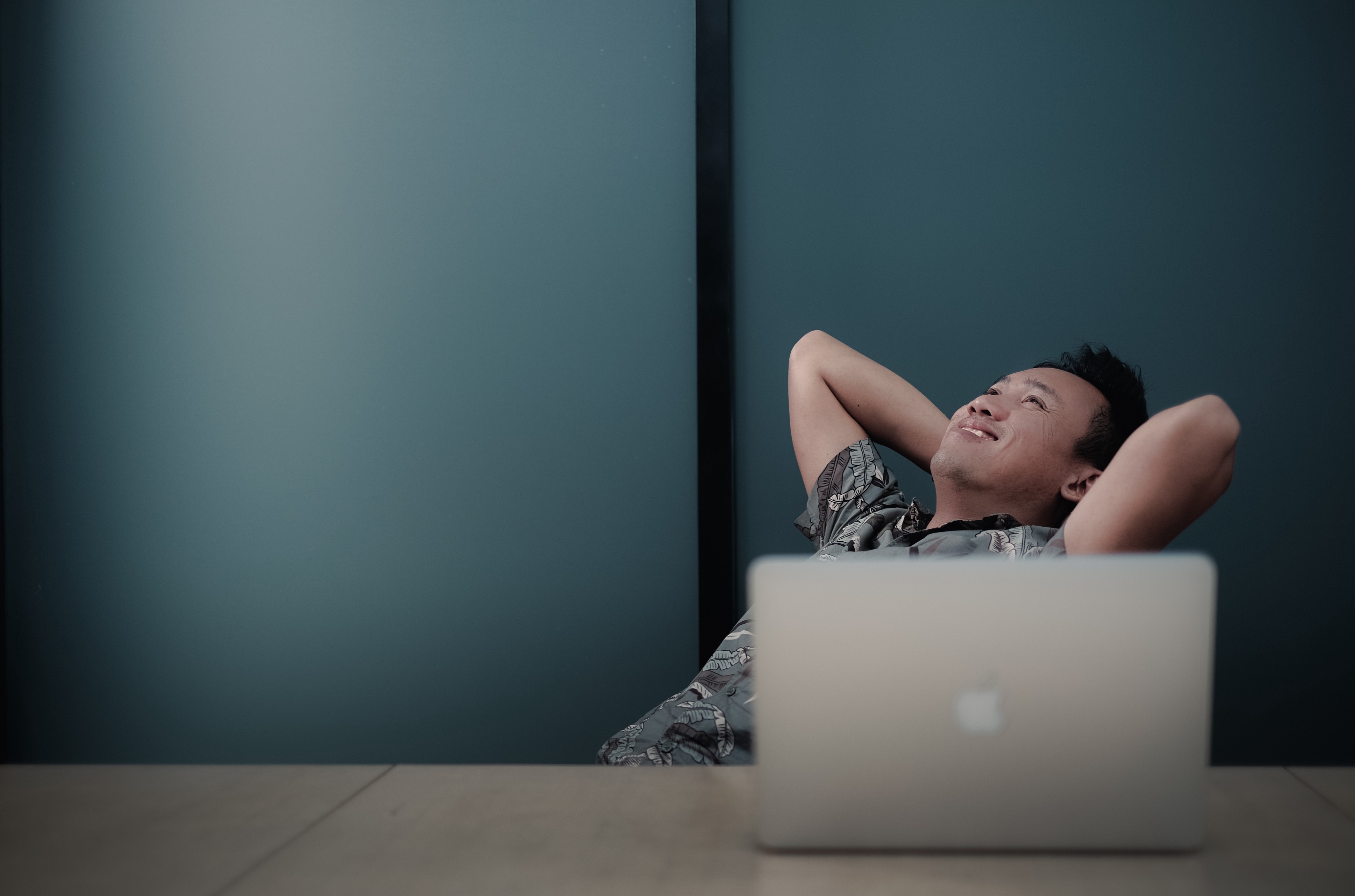 Sitting man with macbook relaxes and smiles in celebration