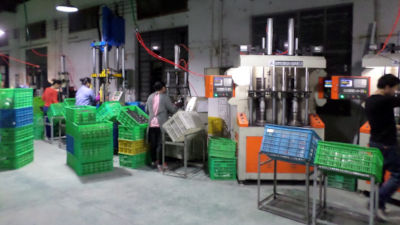 A photo of consumer product mass production line, showcasing many workers each working on a large machine.