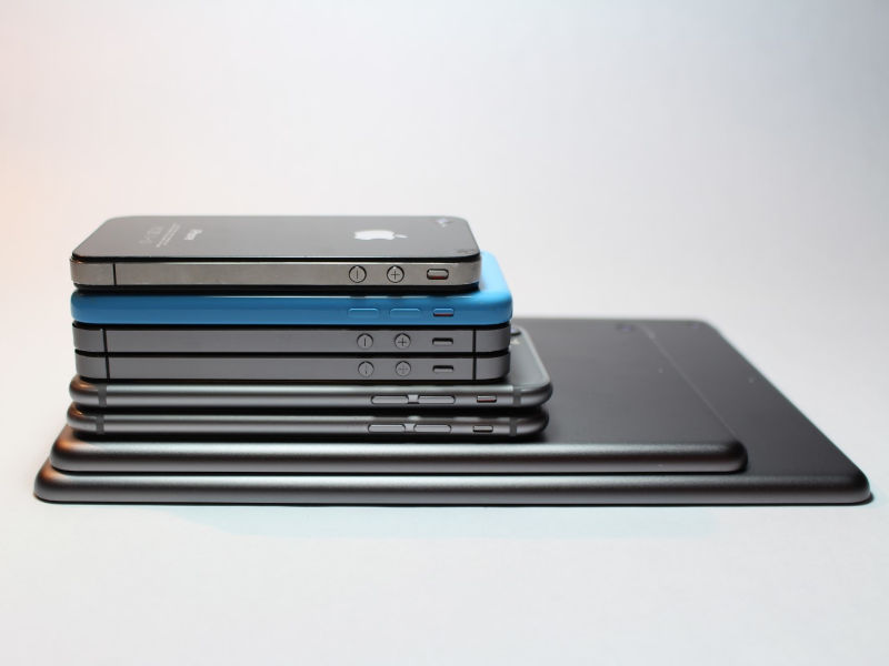 Old iPhones stacked above an iPad.