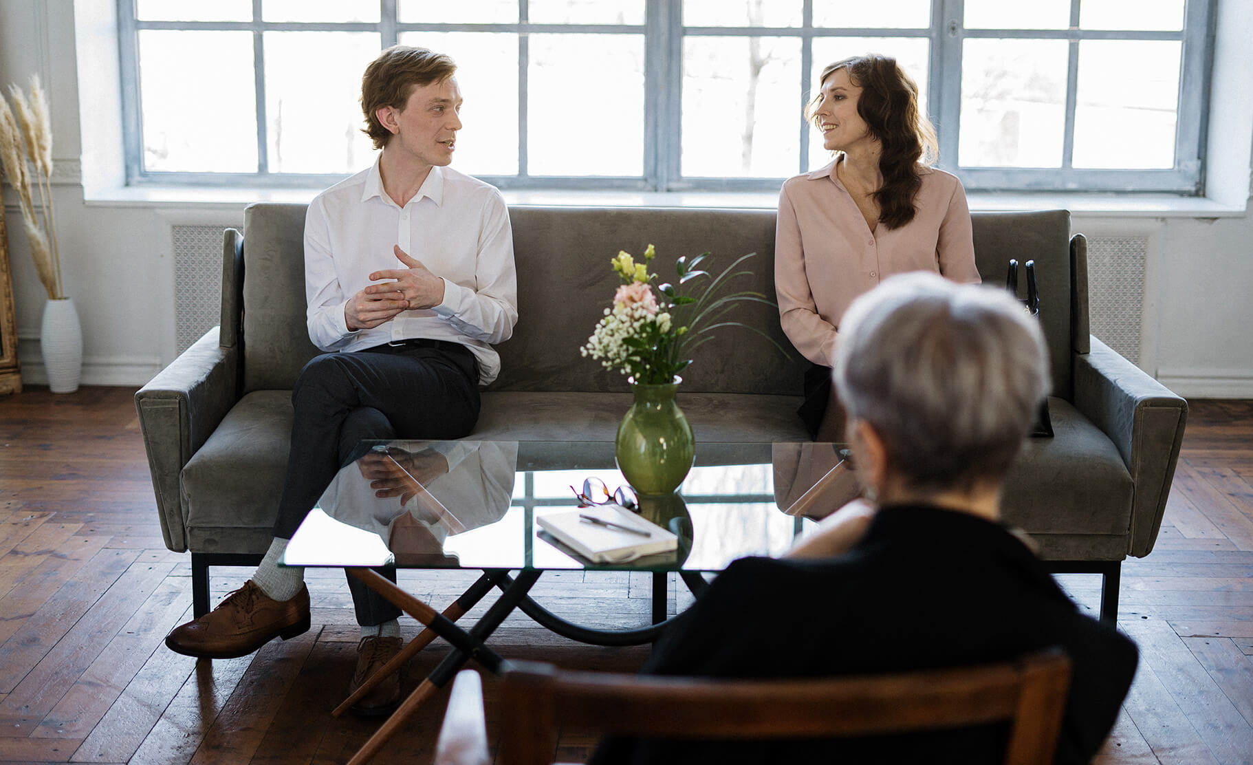 A couple sits on a couch talking opposite a therapist