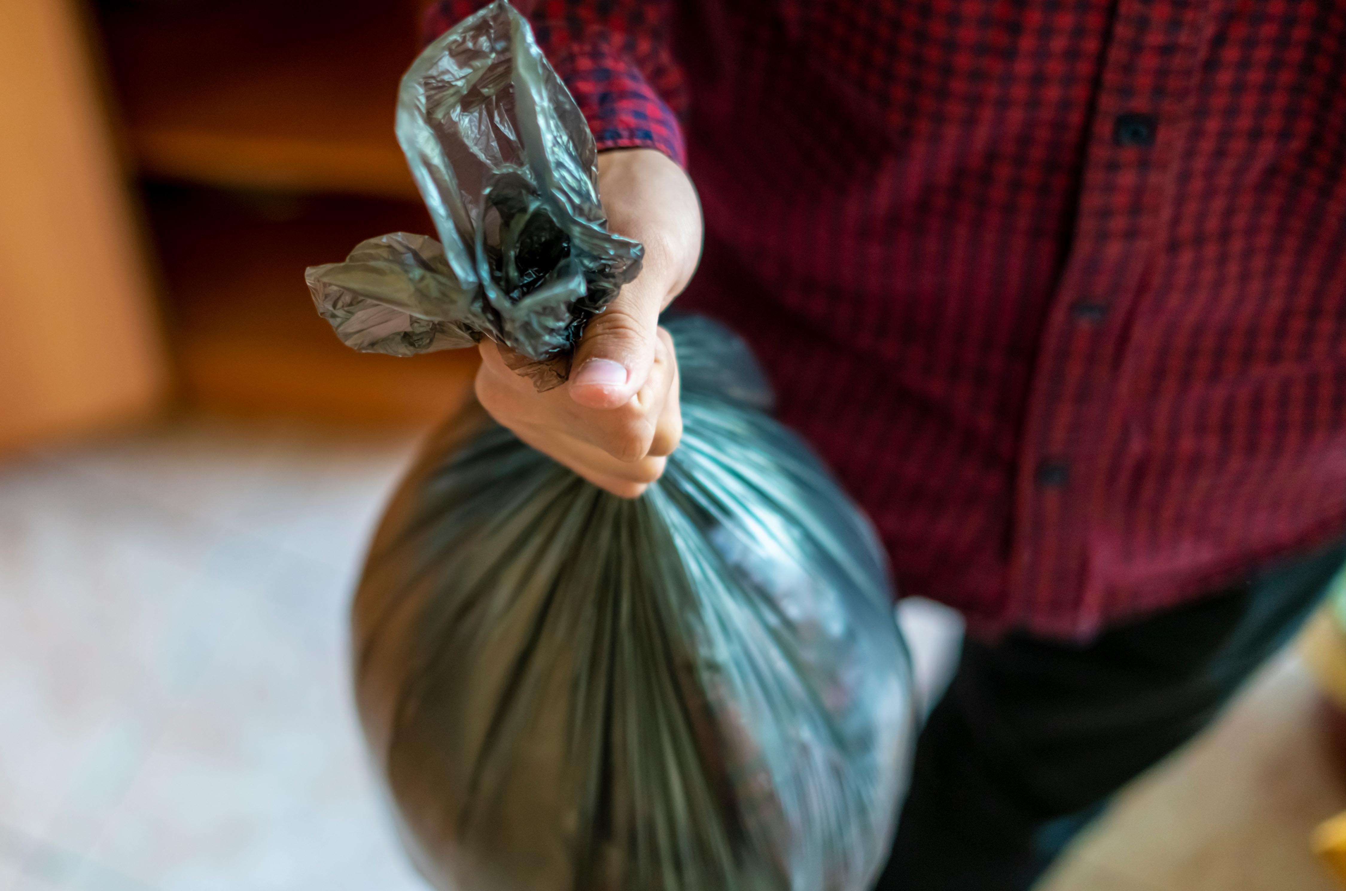 A teen throwing out a garbage bag