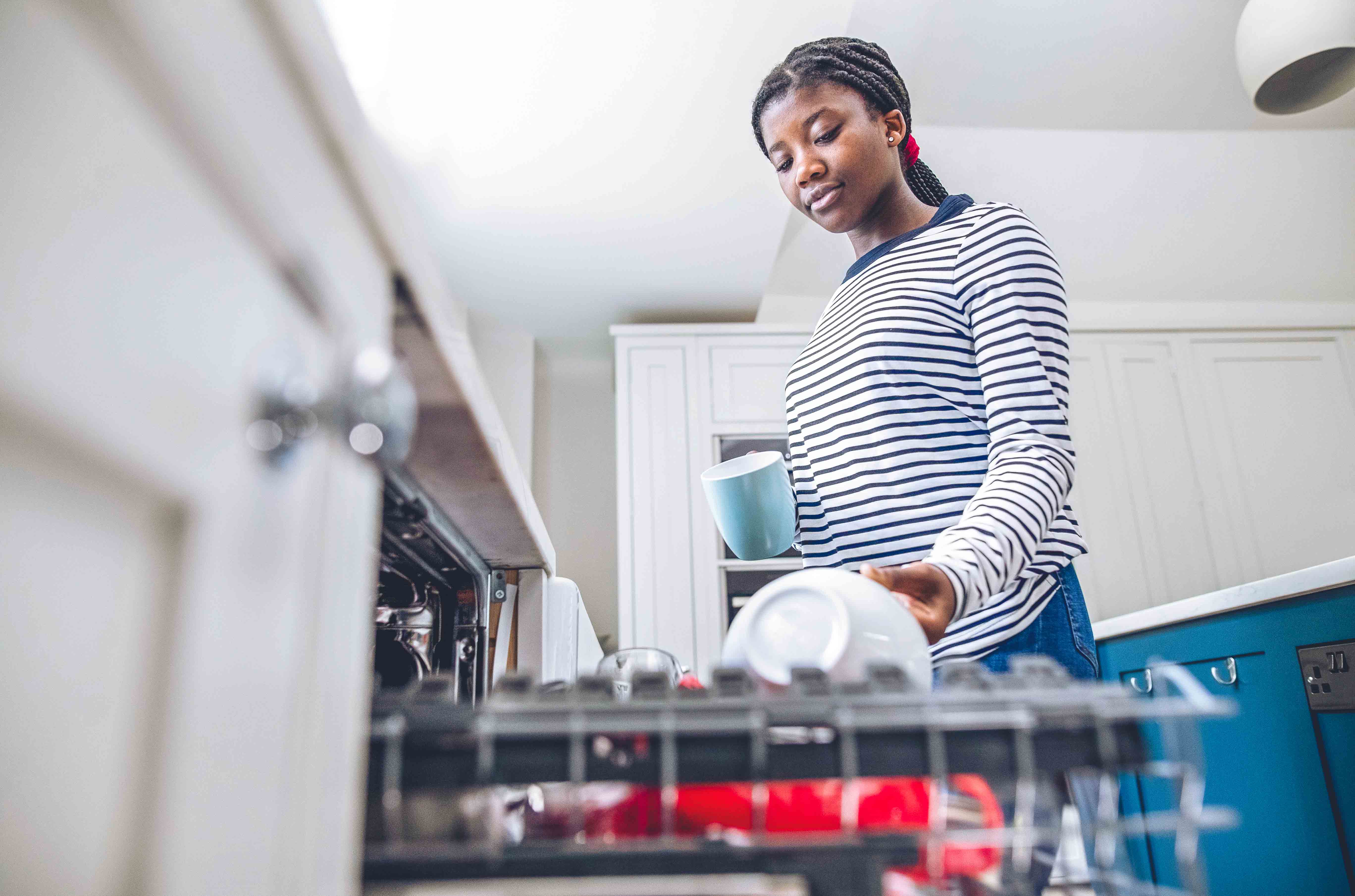 Teenager loading dishwasher