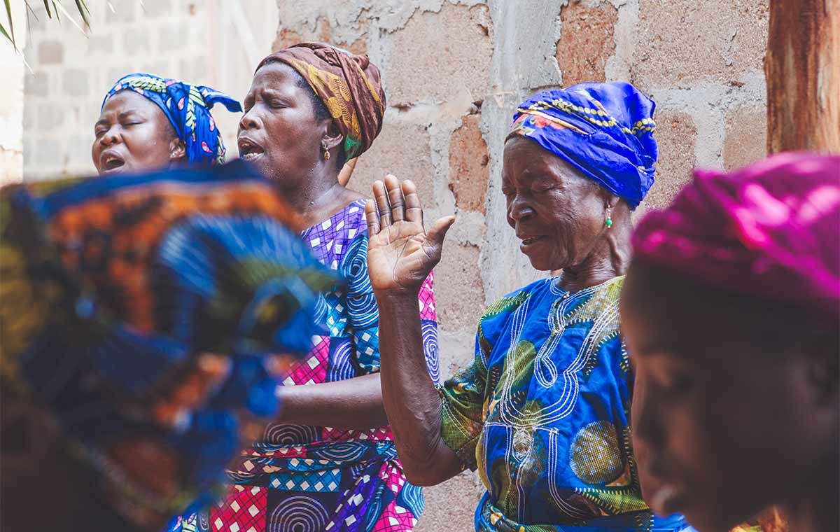 Women in traditional West African clothing singing and dancing