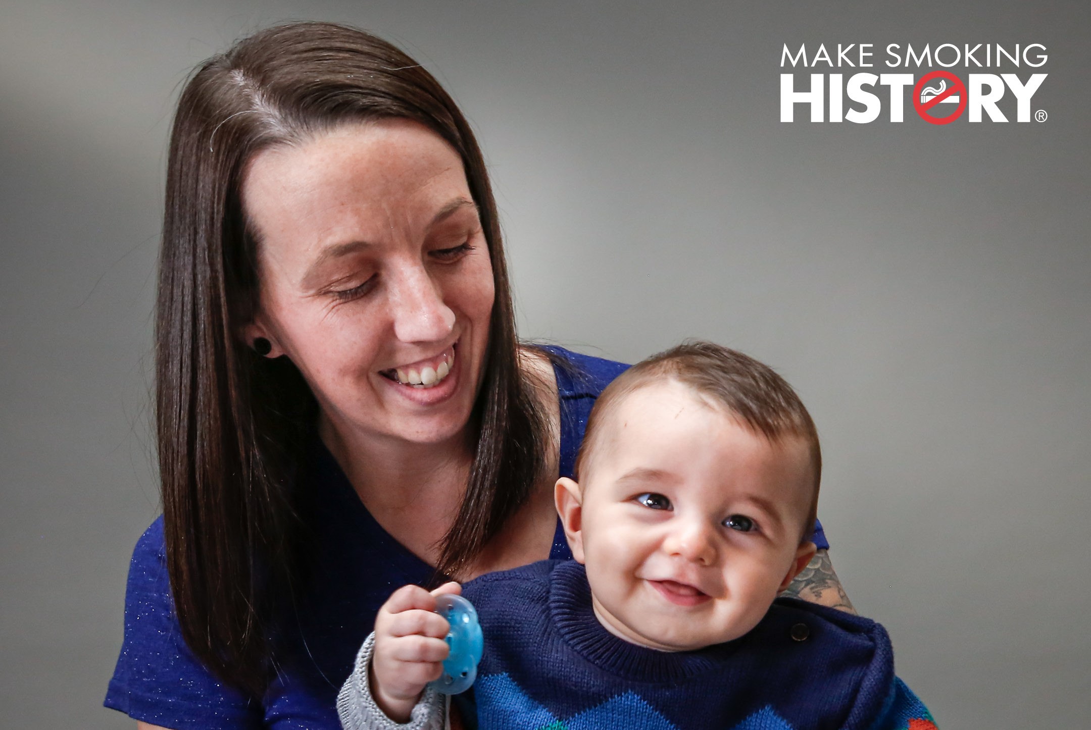 Woman (Levi) holding her baby with Make Smoking History logo in top right hand corner