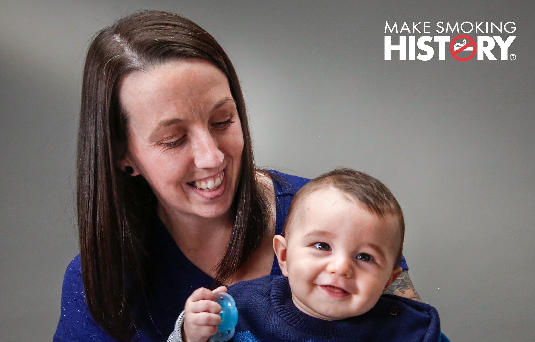Woman (Levi) holding her baby with Make Smoking History logo in top right hand corner