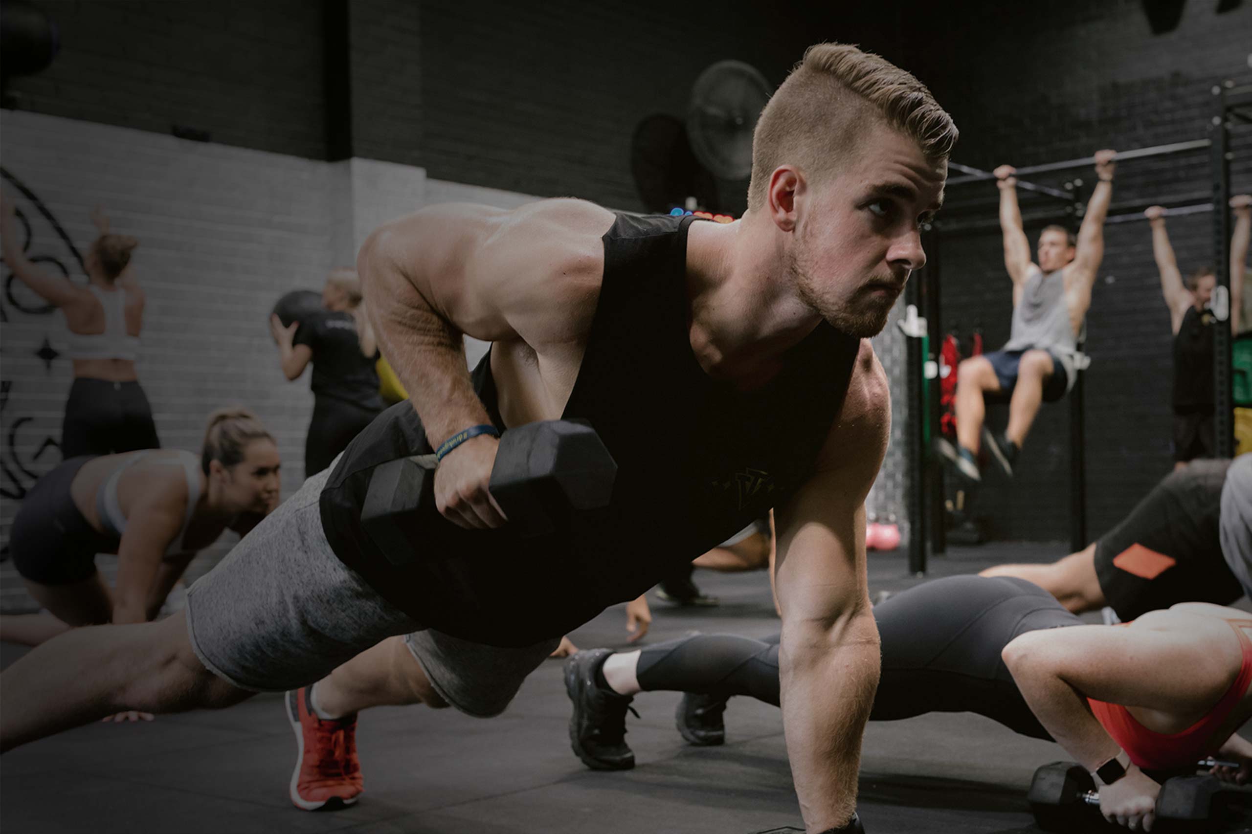 male athlete lifting dumbbells in group training class