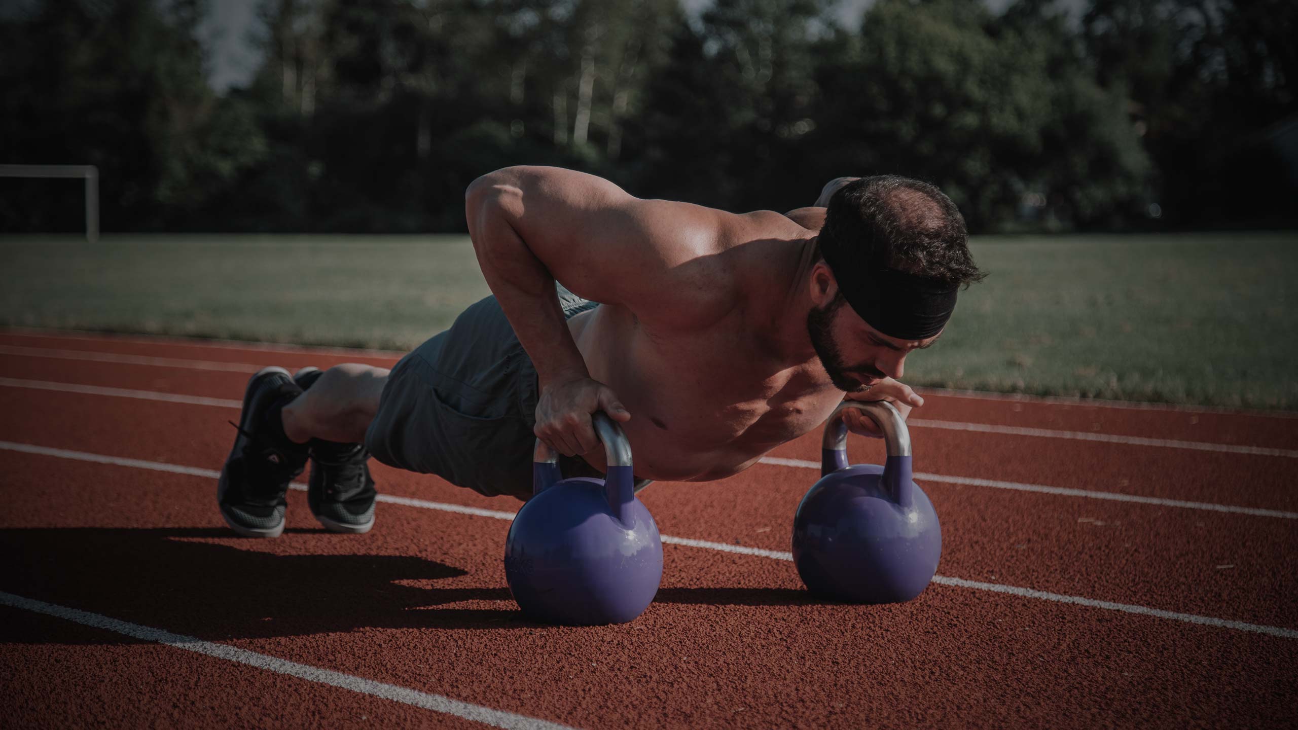 man doing pushups on sporting track field