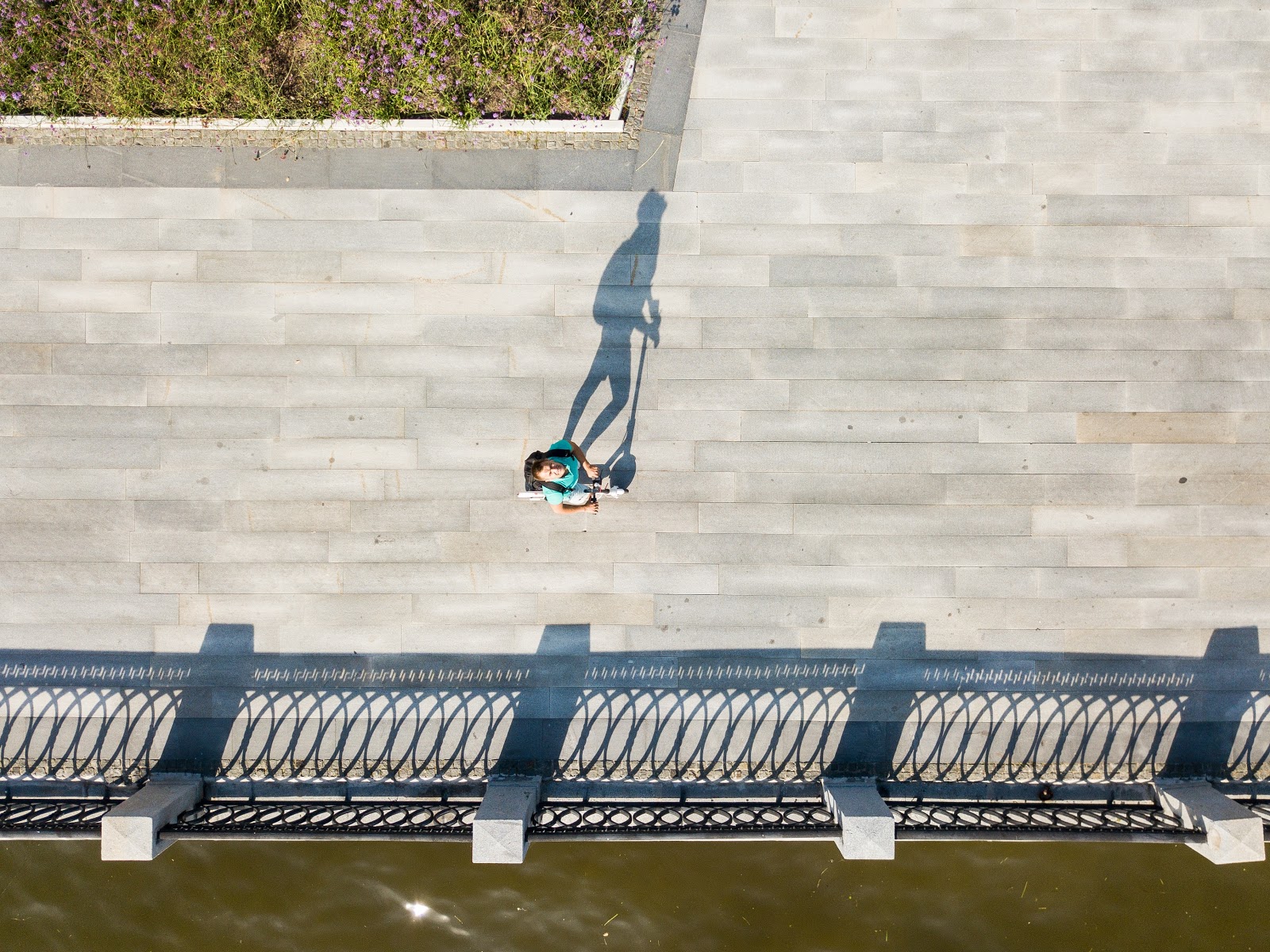 Un hombre mira a la cámara mientras conduce su scooter eléctrico sobre un puente.
