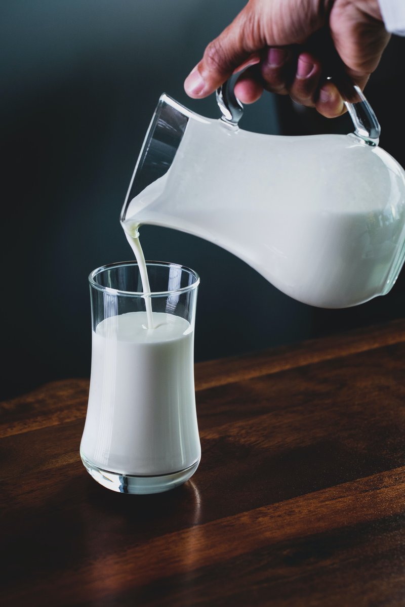 a man pouring milk in the glass from the pitcher
