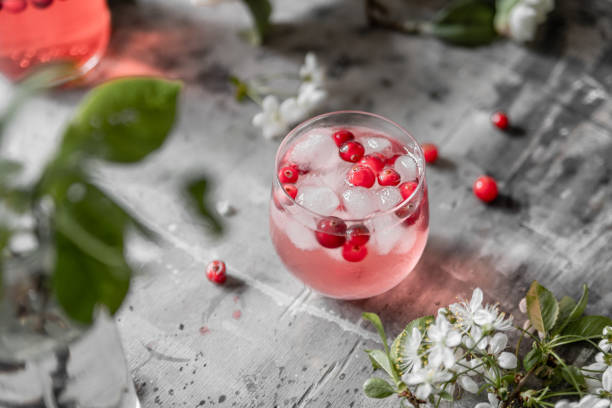 top view spring cranberry lemonade in a glass on a gray shabby table with cherry flowers and leaves - cranberry fizz stock pictures, royalty-free photos & images