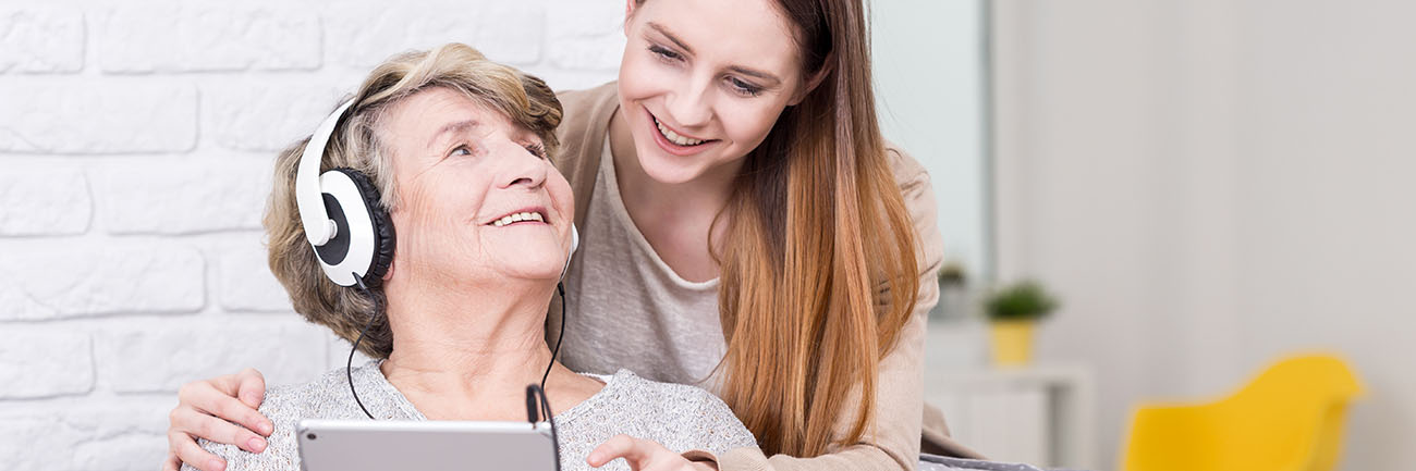 A lady being show how to use a laptop by her grandaughter