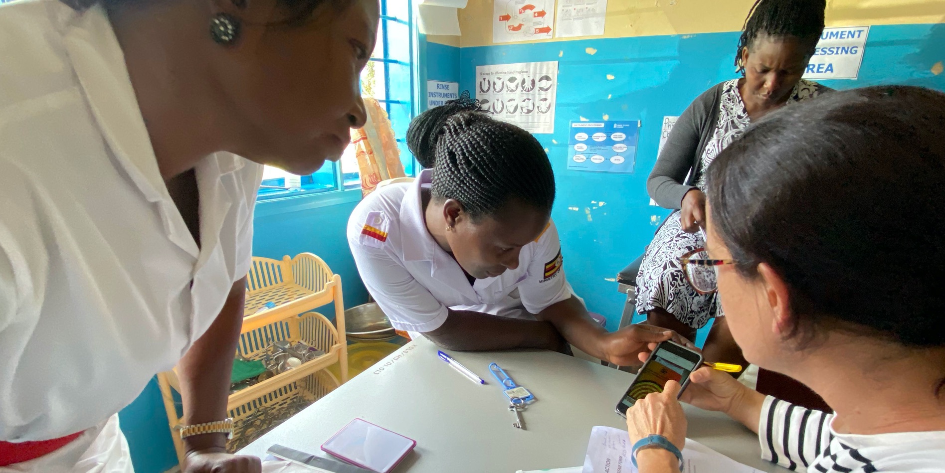 A woman shows two health care officials a mock-up on a smartphone