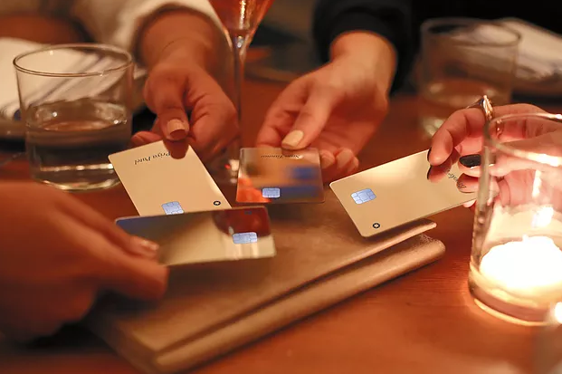 Four women putting their Sequin credit cards in the middle of a table