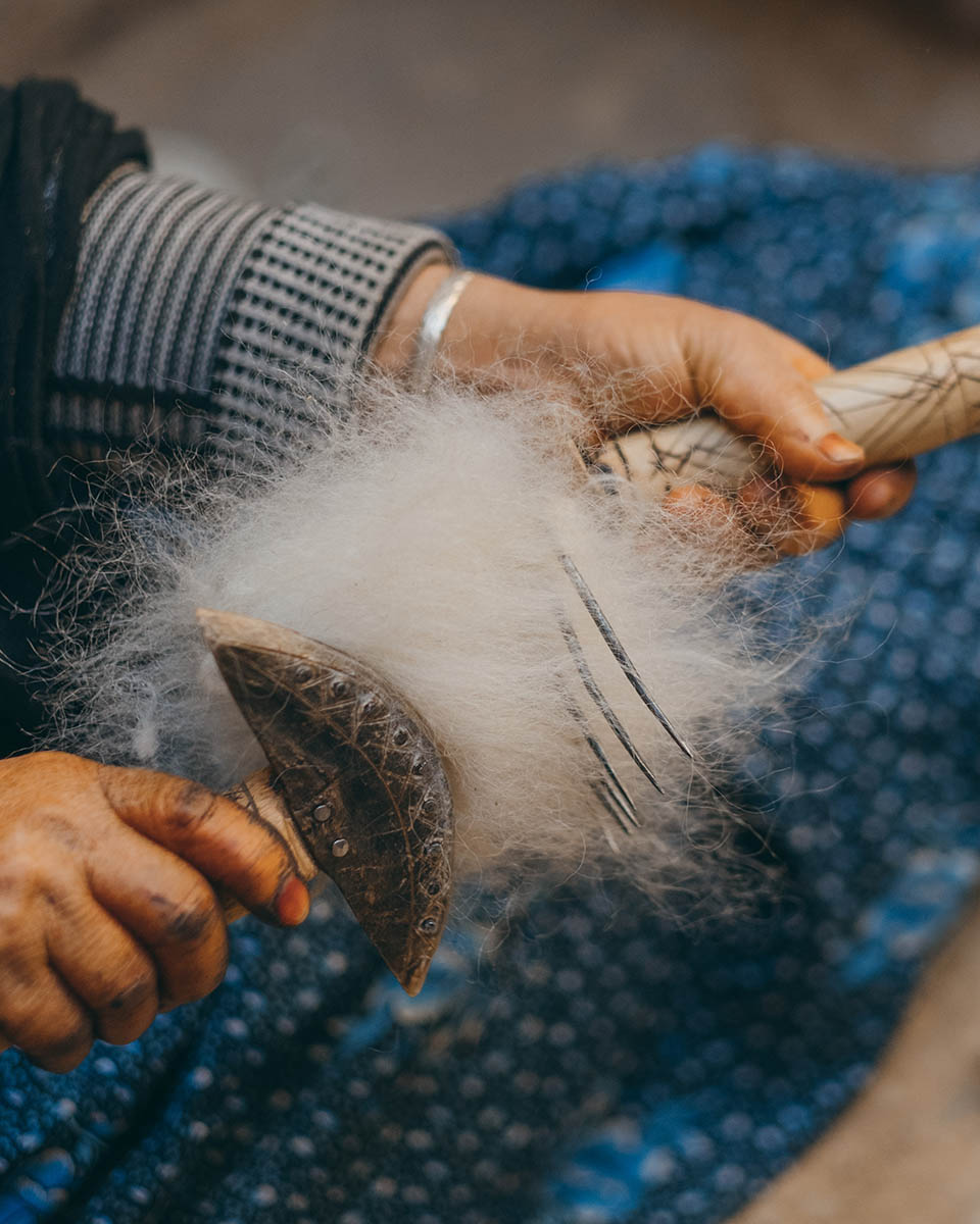 A woman weaver from the Anti Atlas cards the raw wool.