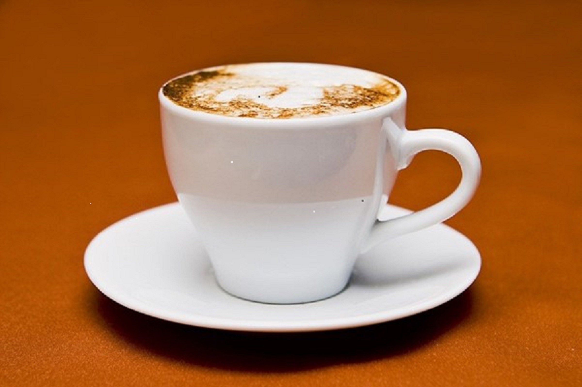 White cup of coffee on a tan background