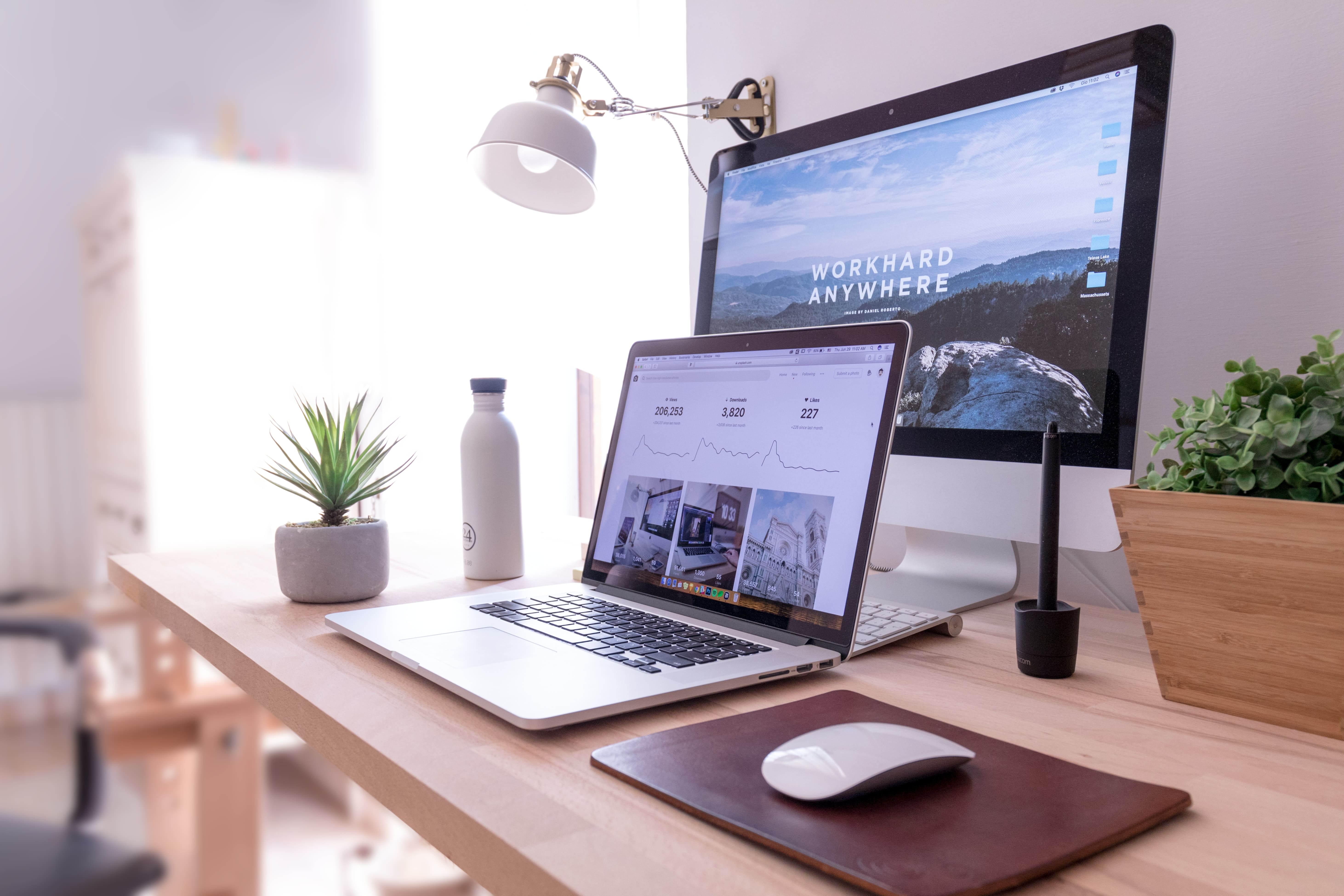 Desk with screen and laptop, screens reafs "Workhard anywhere"