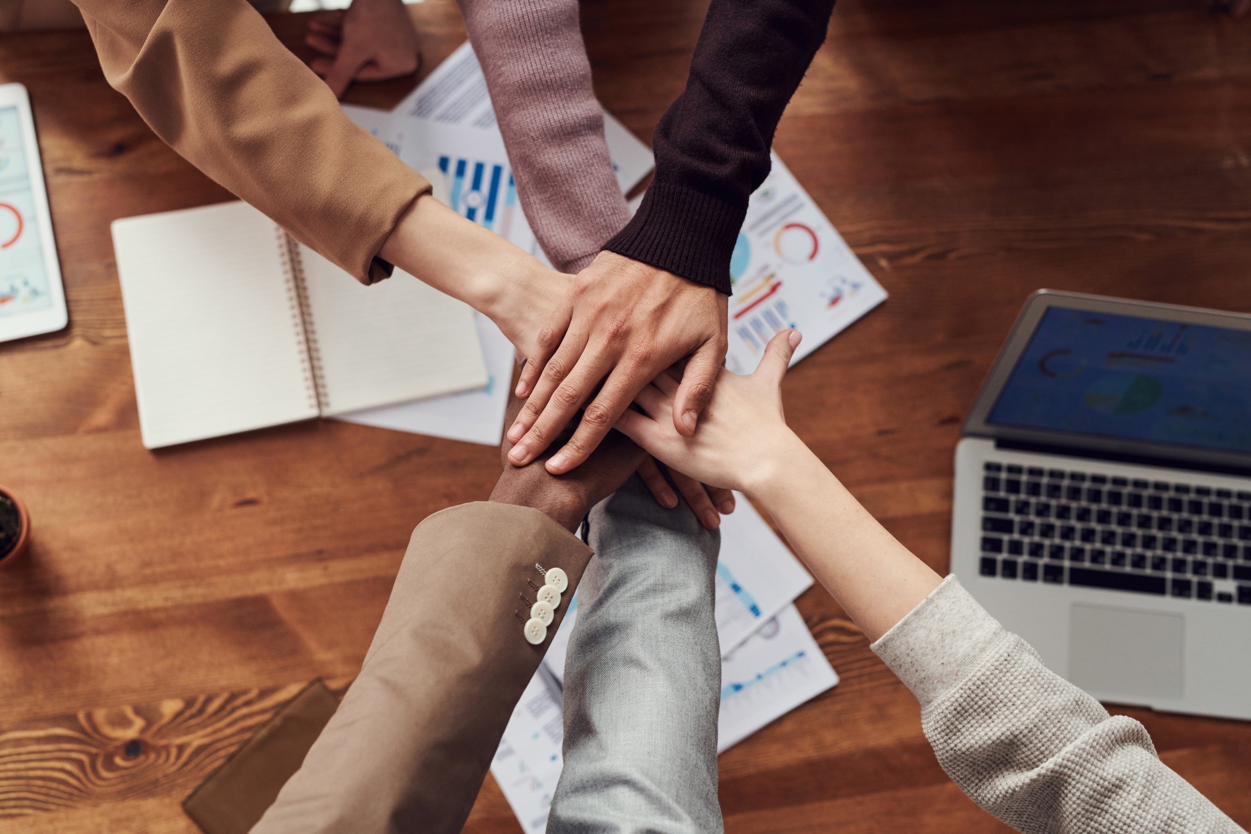 Five people joining hands to symbolize teamwork