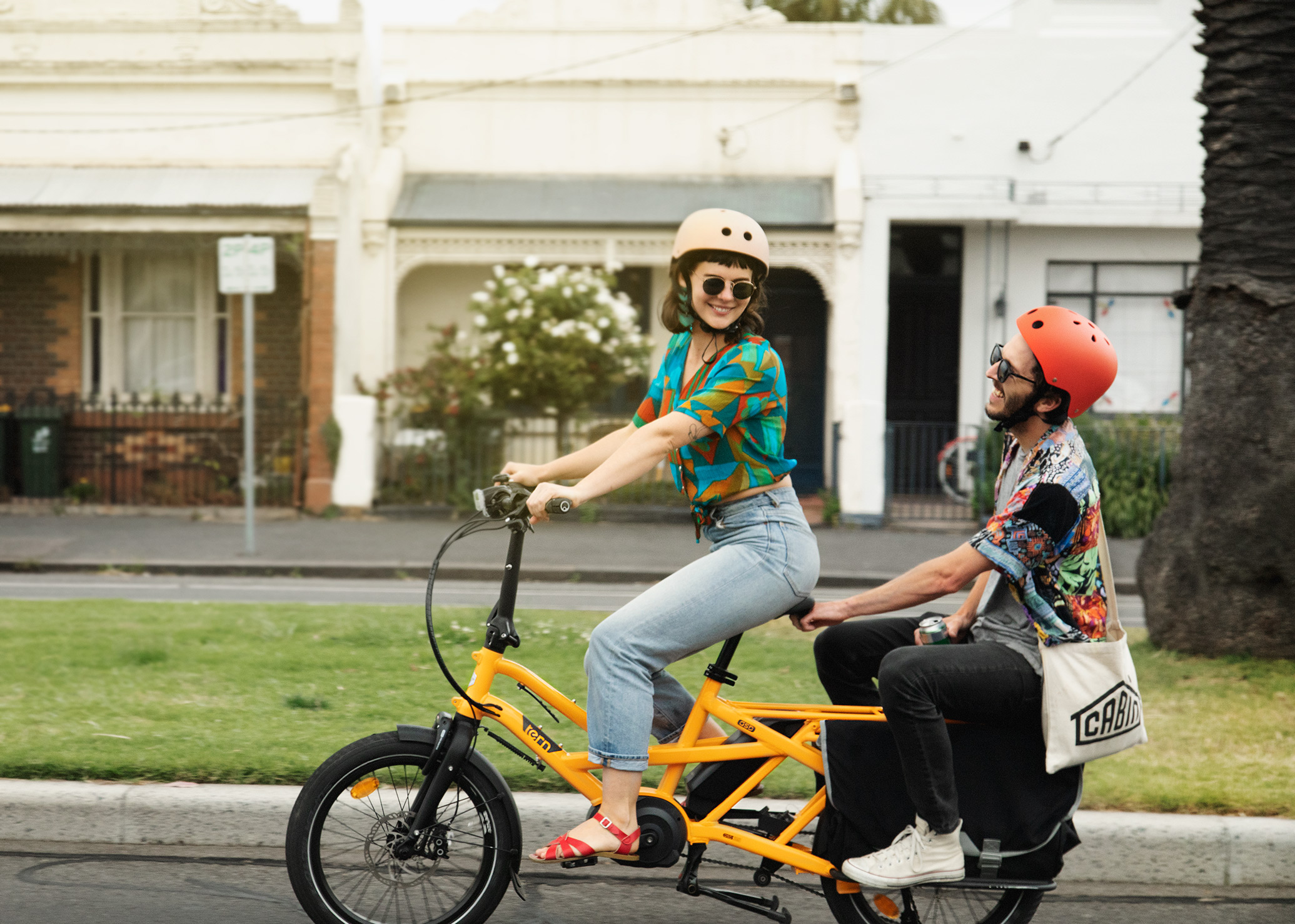a woman rides a yelow Tern GSD with a man riding on the back